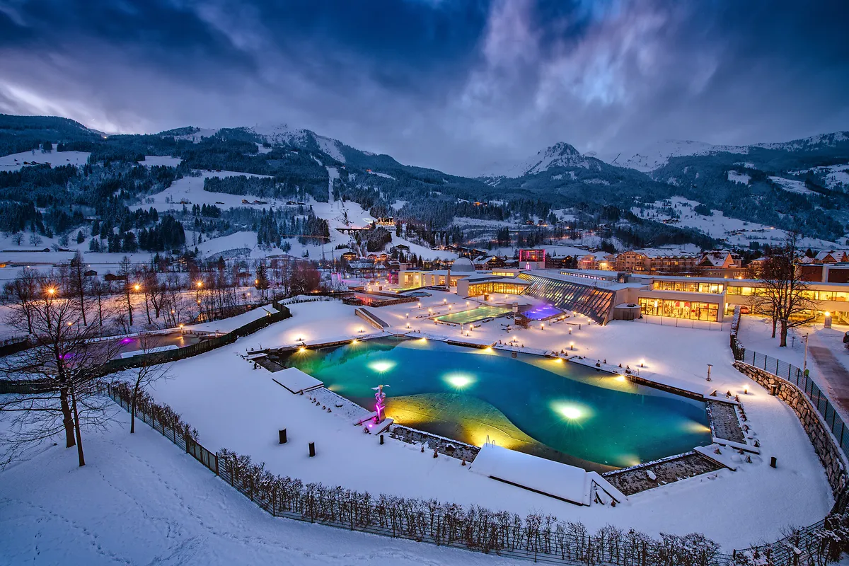 Alpentherme Gastein im Winter mit beleuchteten Thermalbecken und Bergkulisse