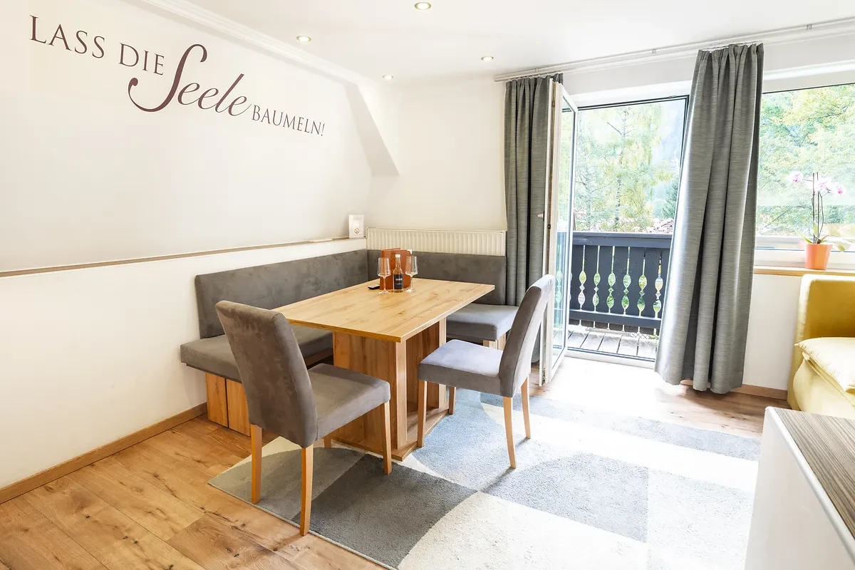 Apartment in Bad Gastein mit Essbank vor geöffneter Balkontür und Blick ins Grüne