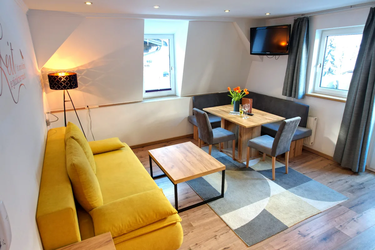 Familienzimmer Bockhartsee – Wohnbereich mit Sitzecke bei GRUBERS Hotel-Apartments Gastein