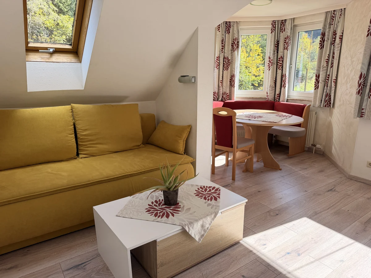 Gelbes Sofa unter der Dachschräge und Couchtisch vor der Essecke im Graukogel