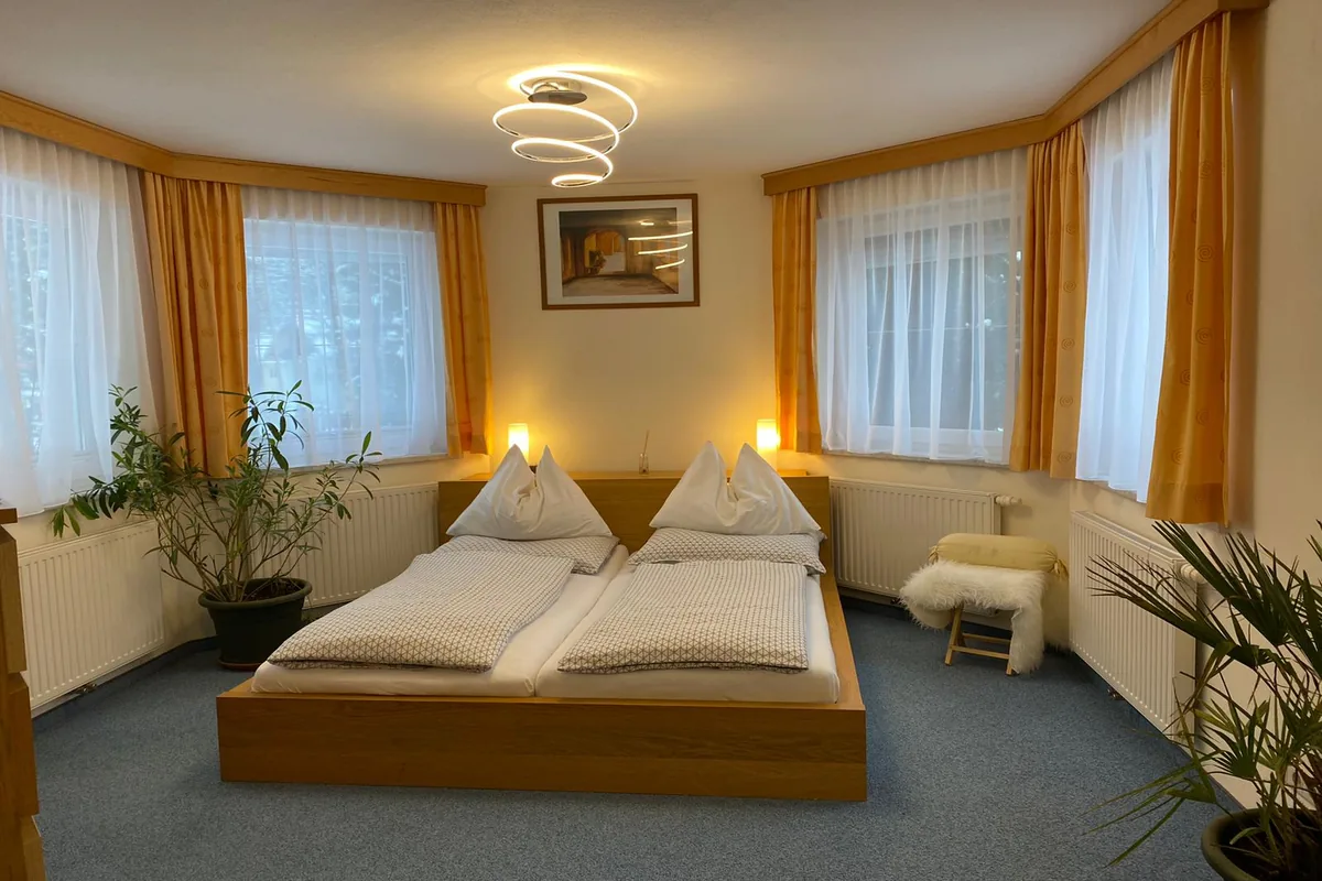 Schlafzimmer der Junior Suite in Bad Gastein mit Doppelbett und stimmungsvollem Licht bei GRUBERS Hotel-Apartments