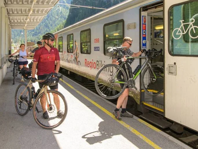 Radreisende verladen ihre Fahrräder in einen ÖBB-Zug am Bahnsteig