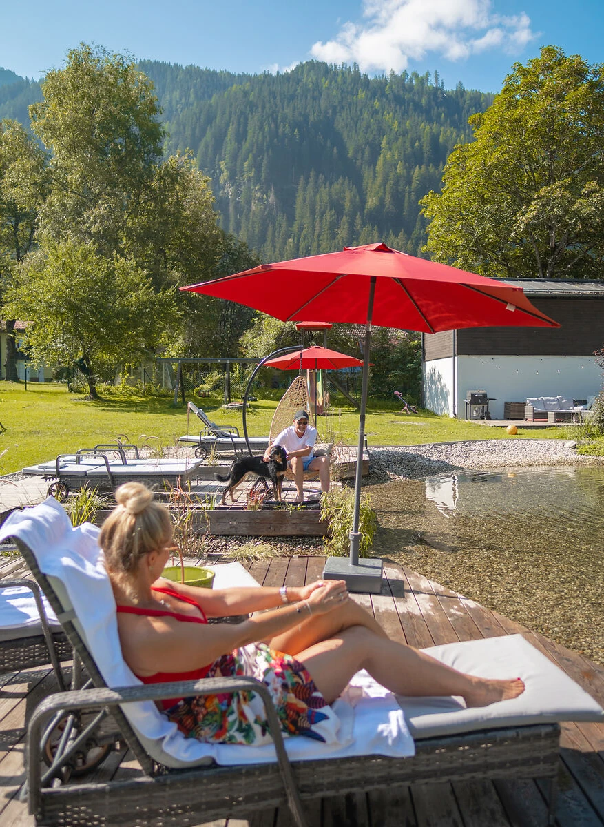 Gäste genießen die Sonne am Hundebadeteich bei GRUBERS Hotel-Apartments in Bad Gastein